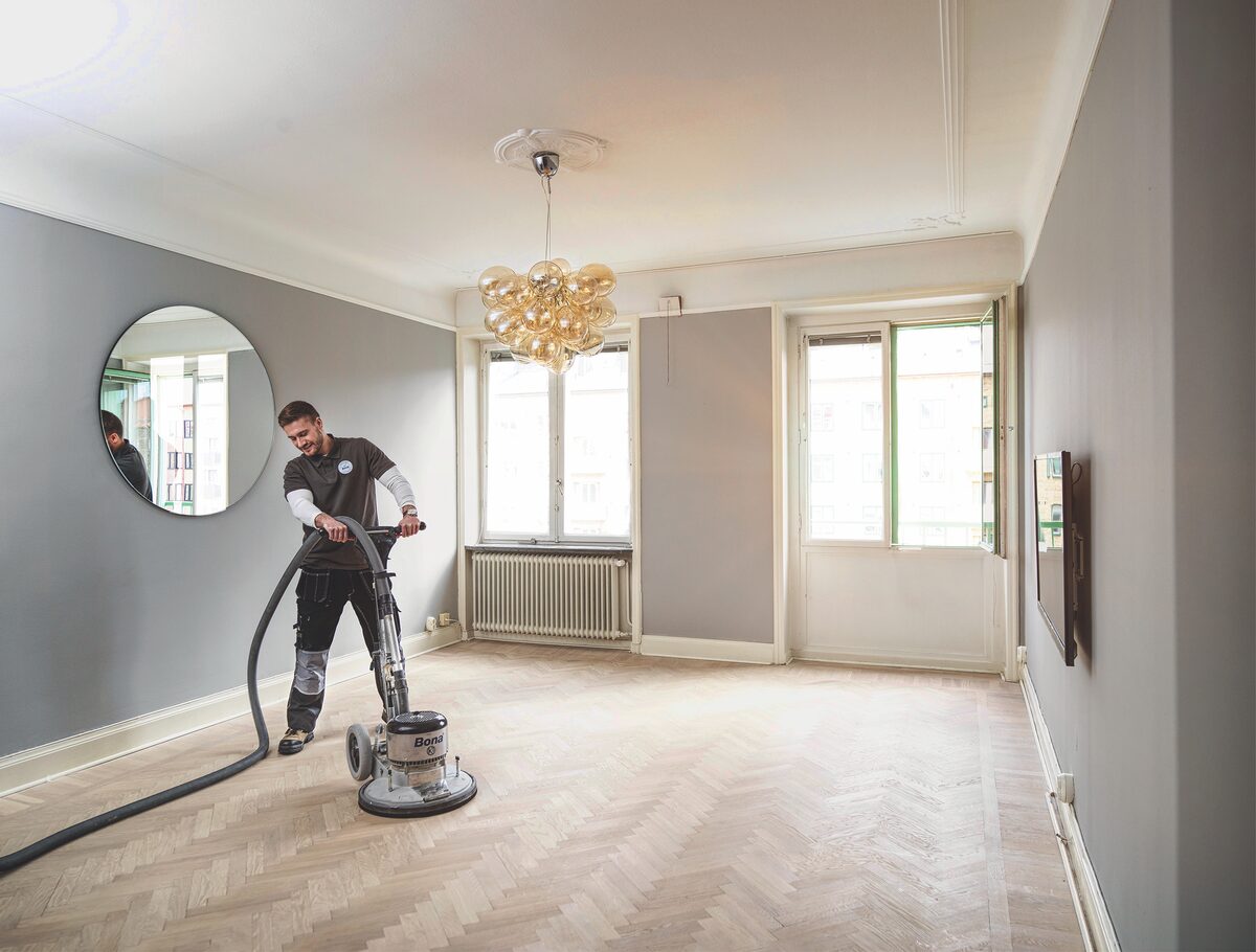 Profissional da Floor raspando piso de madeira com equipamento Bona conectado ao aspirador